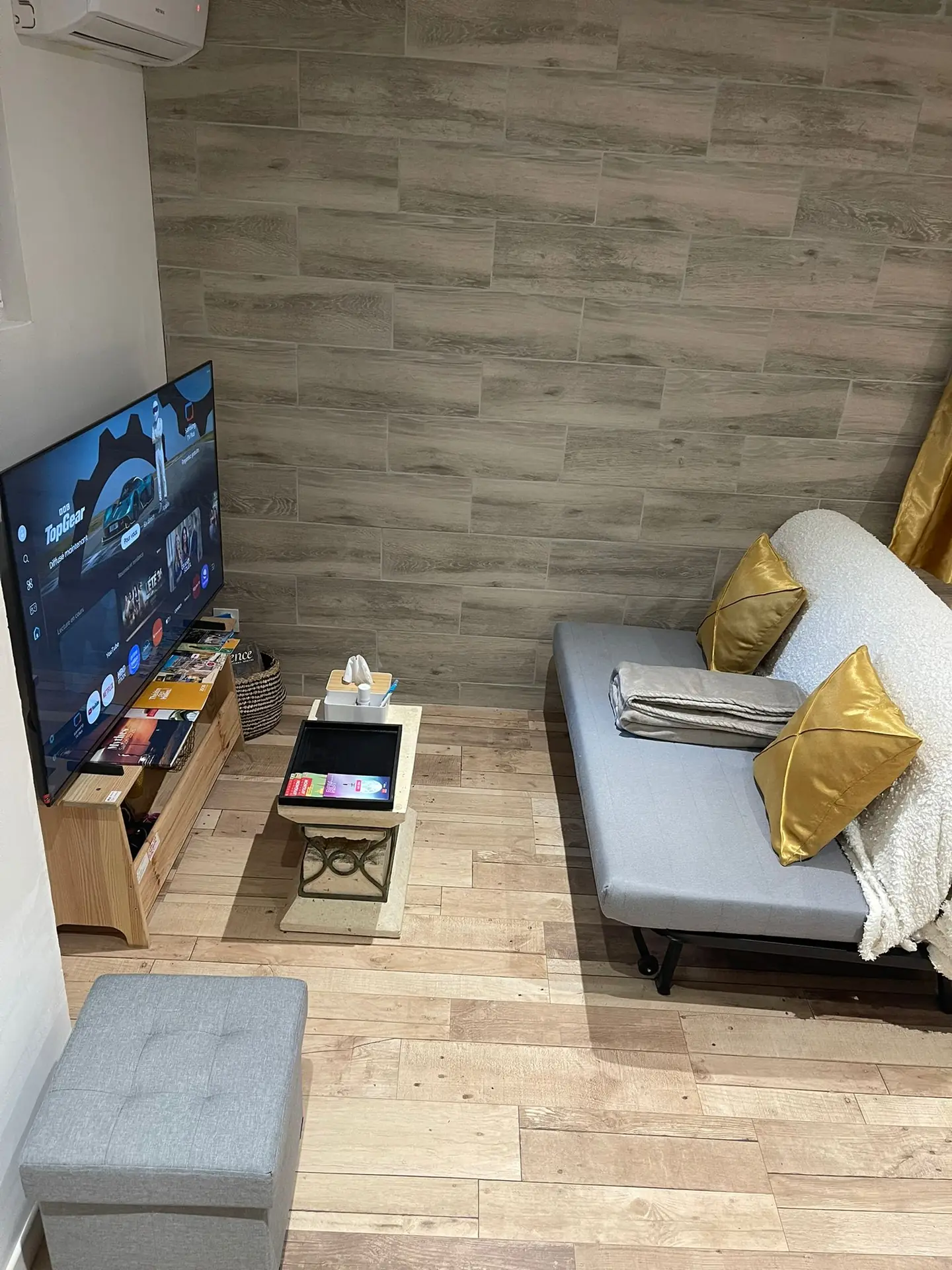 Salon avec canapé gris et télévision